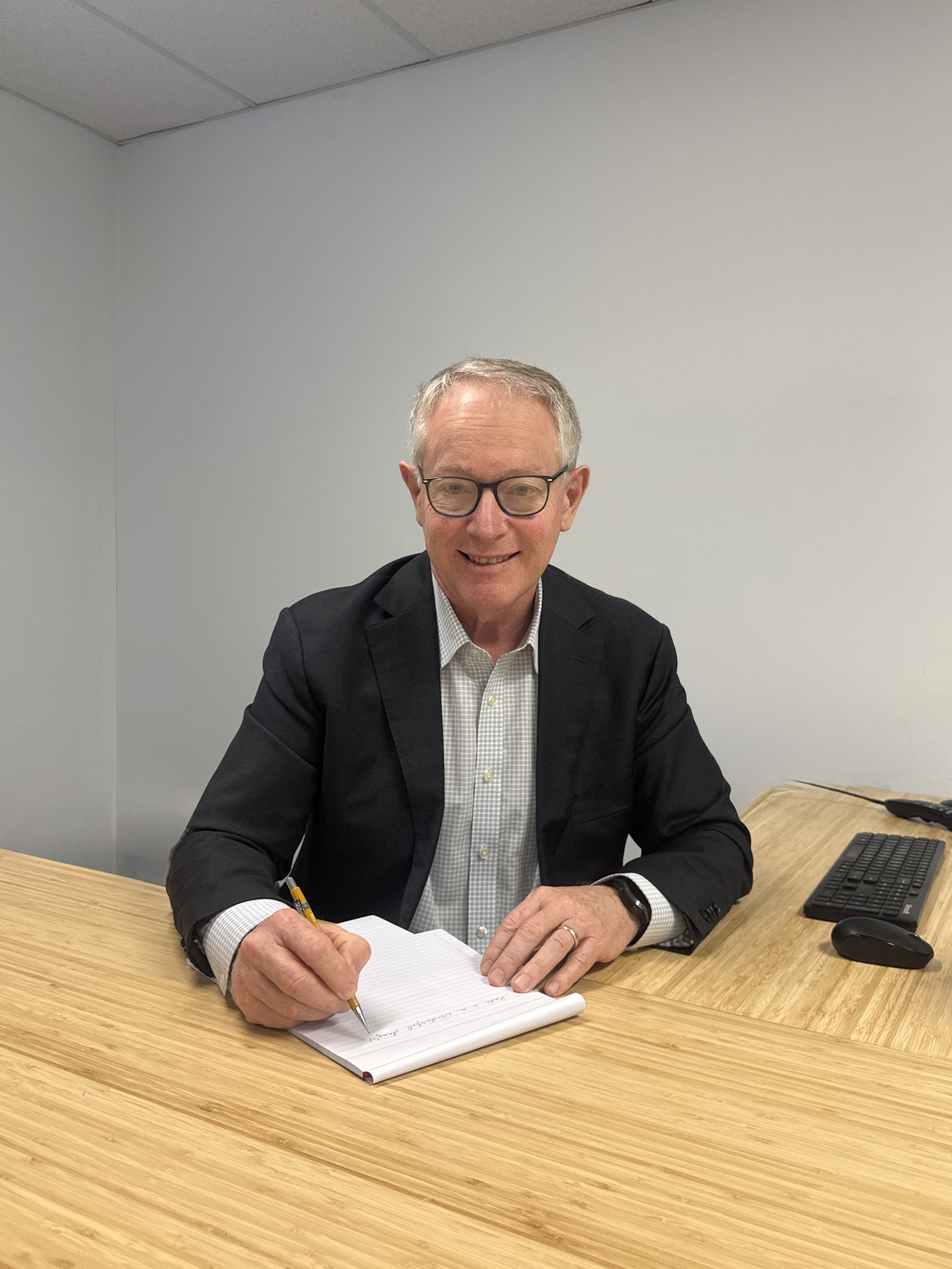 Andrew Lovett seated at his desk with a notebook