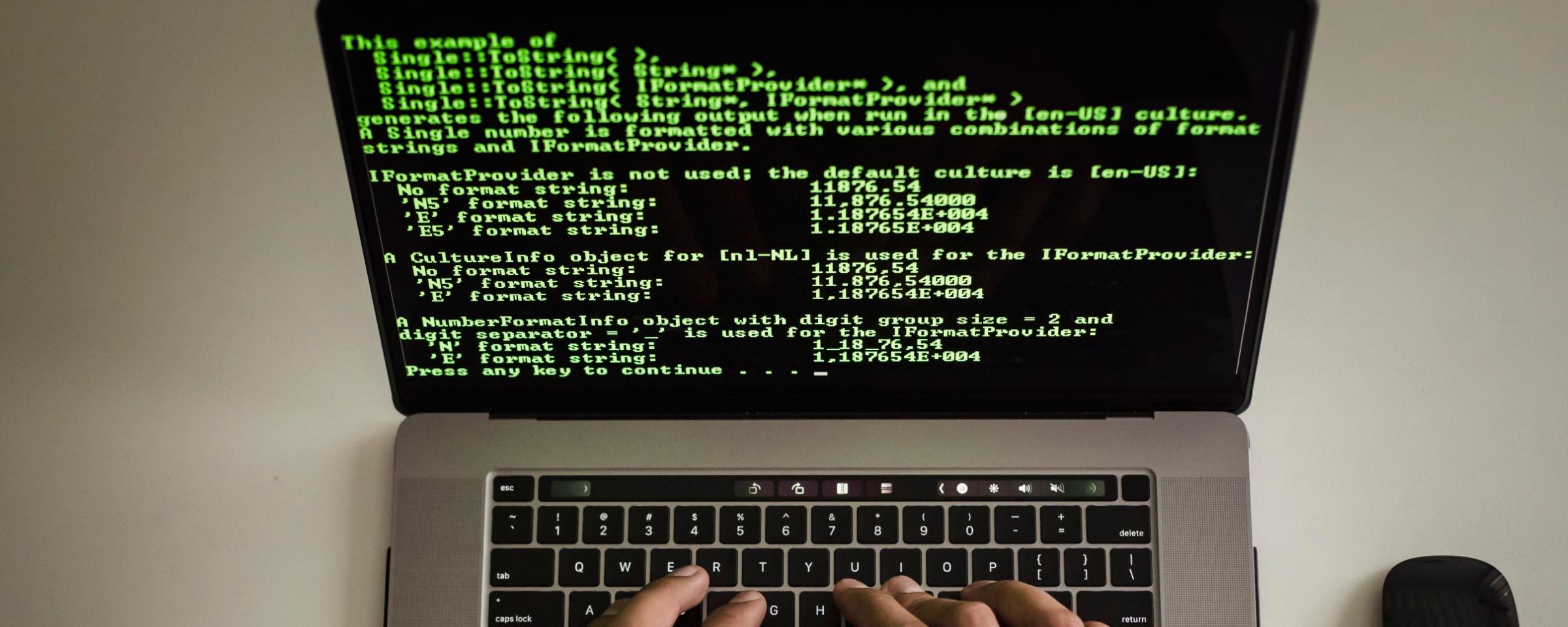 A laptop seen from above, hands at the keyboard, the screen filled with code